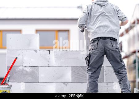 Ein Mauerwerk baut die Wand eines Gebäudes aus Betonziegeln und -Blöcken Stockfoto
