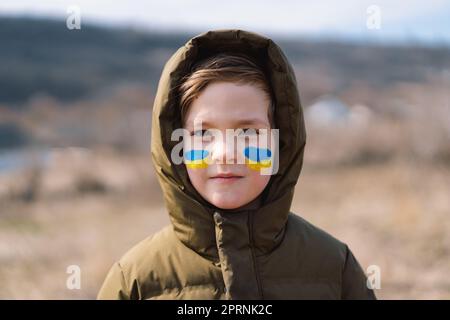 Porträt eines ukrainischen Jungen mit einem Gesicht in den Farben der ukrainischen Flagge. Stockfoto