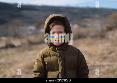 Porträt eines ukrainischen Jungen mit einem Gesicht in den Farben der ukrainischen Flagge. Stockfoto
