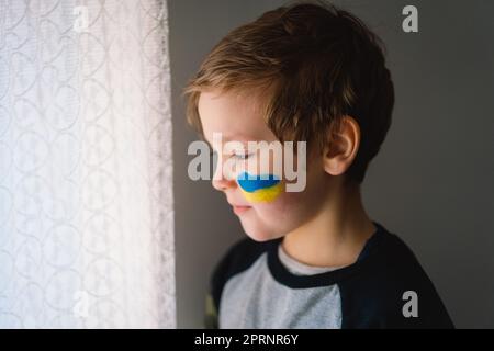 Porträt eines ukrainischen Jungen mit einem Gesicht in den Farben der ukrainischen Flagge. Stockfoto