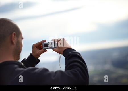 Erinnerungen festhalten. Ein junger Wanderer, der mit seiner Kamera einen Schnappschuss von der Aussicht macht Stockfoto