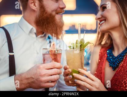 Nahaufnahme eines lächelnden jungen Paares mit zwei Gläsern Cocktails in der Bar Stockfoto