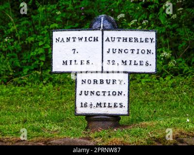 Gusseiserner Wegweiser auf dem Shropshire Union Canal in der Nähe von Audlem in England, der die Entfernung nach Nantwich, Autherley Junction und Norbury Junction anzeigt Stockfoto