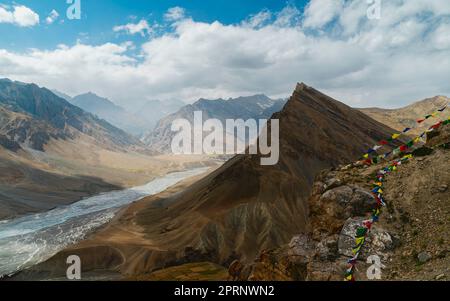 Der Spiti-Fluss, flankiert von hohen Gipfeln des Himalaya unter einem blauen, wolkigen Himmel nahe Kaza, Himachal Pradesh, Indien. Stockfoto