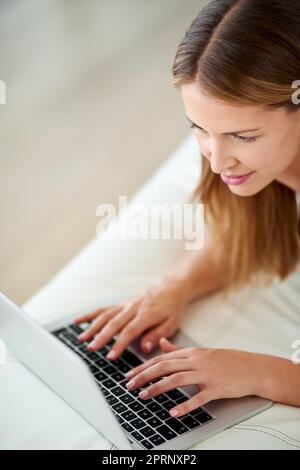 Online vom Sofa aus. Eine junge Frau, die zu Hause im Internet surft. Stockfoto