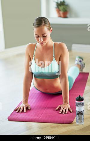 Beginn ihrer Yoga-Routine. Eine attraktive junge Frau, die zu Hause Yoga macht. Stockfoto