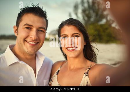 Selfies im Paradies. Verkürztes Porträt eines liebevollen jungen Paares, das Selfies macht, während er am Strand steht Stockfoto