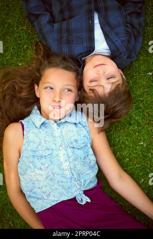 Die ihren Atem am längsten anhalten können. Hochwinkelige Aufnahme eines jungen Bruders und einer Schwester, die draußen auf dem Gras liegen und den Atem anhalten. Stockfoto