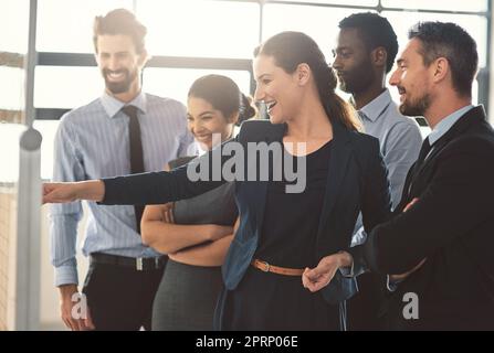 Alle Hände auf Deck für dieses Treffen. Eine Gruppe von Geschäftsleuten Blick über Pläne auf einem Whiteboard. Stockfoto