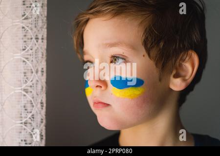 Porträt eines ukrainischen Jungen mit einem Gesicht in den Farben der ukrainischen Flagge. Stockfoto