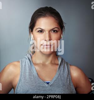 Das Geheimnis ist Hingabe. Beschnittene Studioaufnahme einer sportlichen jungen Frau vor grauem Hintergrund. Stockfoto