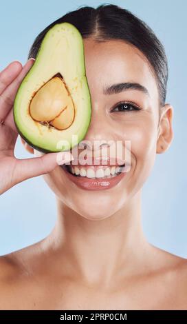 Avocado-, Wellness- und Hautpflege-Frau Porträt auf blauem Studiohintergrund und Modell. Junges Modell mit natürlicher Bio-Ernährung für Gesicht und Gesundheit mit grünem, sauberem und gesundem Lebensstil Stockfoto