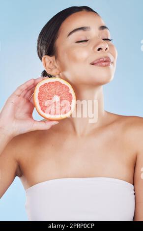 Grapefruit, Frauen Hautpflege und Wellness Frucht für Gesichtspflege, Wellness und Diät Gesundheit auf blauem Hintergrund im Studio. Fröhliches, lächelndes und schönes brasilianisches Modell mit Vitamin-C-Nahrungsmitteln in den Händen Stockfoto