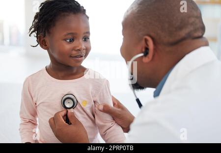 Gesundheitswesen, Kinderarzt und Kinderherzarzt mit einem Patienten im Krankenhaus, Untersuchung auf der Brust mit einem Stethoskop. Schwarzes Mädchen lächelt Kinderchirurg an, spricht mit einem freundlichen, fürsorglichen Arzt, dem sie vertraut Stockfoto