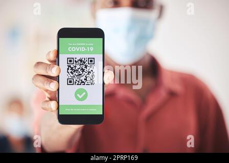 Covid, QR-Code und Telefon in der Hand für geimpfte digitale Verifizierungszertifikate oder Reisepass in einem Flughafen, Krankenhaus oder einer Klinik. Mann mit Smartphone- und Bildschirmtechnologie für Coronavirus-Sicherheit Stockfoto