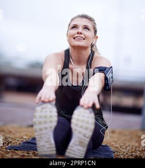 Bereit für die Fahrt. Eine junge Frau, die ihre Beine vor einem Lauf streckt. Stockfoto