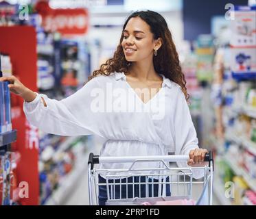 Kunden, Käufer und Verbraucher, die Lebensmittel in einem Supermarkt, einem Einkaufszentrum oder einem Einzelhandelsgeschäft kaufen. Glückliche Frau, die den Wagen in den Gang schiebt, um Verkaufsprodukte, Rabattwaren und Markenangebote zu kaufen Stockfoto