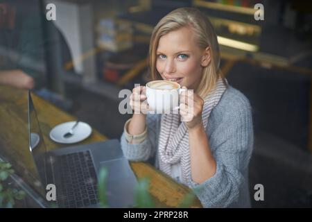 Wir alle brauchen einen Ort, um alleine zu sein. Eine junge Frau, die in einem Café sitzt. Stockfoto