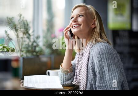 Wir alle brauchen einen Ort, um alleine zu sein. Eine junge Frau, die in einem Restaurant sitzt und auf ihrem Handy spricht. Stockfoto