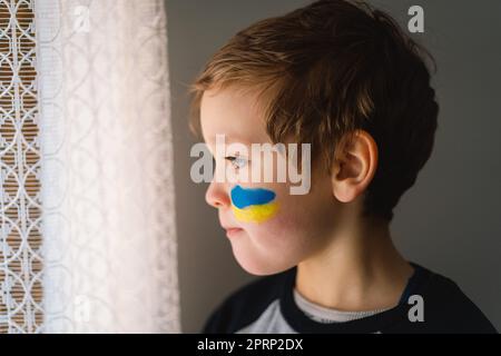 Porträt eines ukrainischen Jungen mit einem Gesicht in den Farben der ukrainischen Flagge. Stockfoto