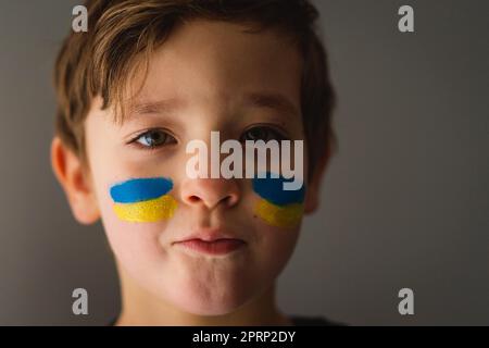 Porträt eines ukrainischen Jungen mit einem Gesicht in den Farben der ukrainischen Flagge. Stockfoto