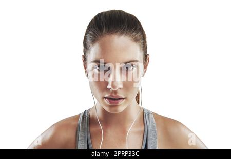 Musik motiviert mich. Beschnittenes Porträt einer jungen Sportlerin, die vor weißem Hintergrund Musik hört. Stockfoto