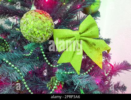 Nahaufnahme eines Weihnachtsbaums mit Schleifen, glitzernden Glaskugeln und Weihnachtsbaumspielzeug Stockfoto