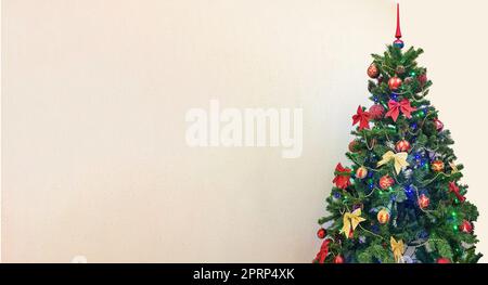 Ein festliches Foto eines Weihnachtsbaums mit bunten Verzierungen, hervorgehoben auf weißem Hintergrund mit einer Kopie des Bereichs auf der linken Seite Stockfoto