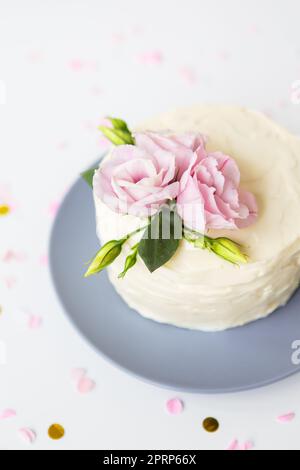 Sehr schöner kleiner weißer Kuchen dekoriert mit frischen Eustoma-Blumen. Urlaubskonzept. Stockfoto