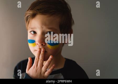 Porträt eines ukrainischen Jungen mit einem Gesicht in den Farben der ukrainischen Flagge. Stockfoto