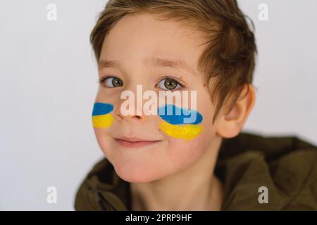 Porträt eines ukrainischen Jungen mit einem Gesicht in den Farben der ukrainischen Flagge. Stockfoto