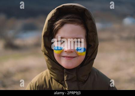 Porträt eines ukrainischen Jungen mit einem Gesicht in den Farben der ukrainischen Flagge. Stockfoto