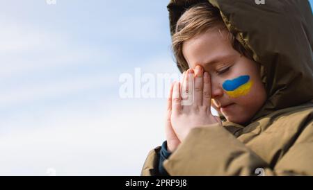 Der ukrainische Junge schloss die Augen und betete, den Krieg in der Ukraine zu beenden. Stockfoto