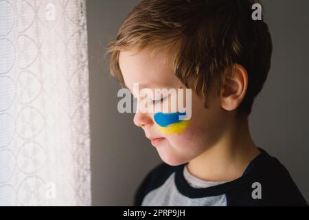 Porträt eines ukrainischen Jungen mit einem Gesicht in den Farben der ukrainischen Flagge. Stockfoto