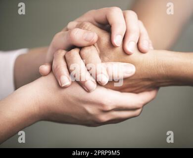 Du brauchst keinen Grund, anderen zu helfen. Zwei Personen, die bequem Händchen halten Stockfoto