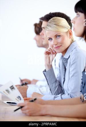 Zufrieden mit meiner Arbeit. Porträt einer hübschen Geschäftsfrau, die während einer Vorstandssitzung vor der Kamera lächelt Stockfoto