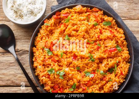 Traditioneller türkischer Meyhane pilavi bulgur Pilaf mit Tomatensaison, Nahaufnahme auf einem Teller auf einem Holztisch. Horizontale Draufsicht von oben Stockfoto