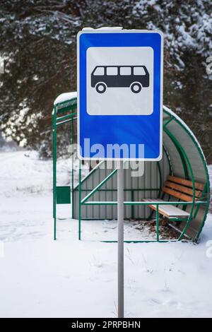 Bushaltestelle in der Mitte einer schönen Winterstraße Mitten im Wald mit Bushaltestelle zeichen Stockfoto