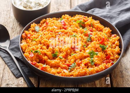 Traditioneller türkischer Meyhane pilavi bulgur Pilaf mit Tomatensaison, Nahaufnahme auf einem Teller auf einem Holztisch. Horizontal Stockfoto