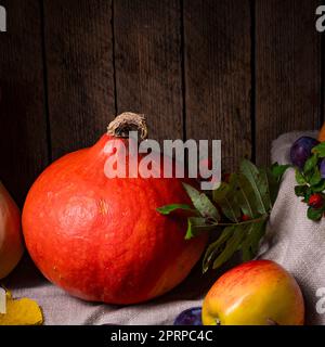 Verschiedene Früchte in einer Holzkiste mit Herbstblättern Stockfoto