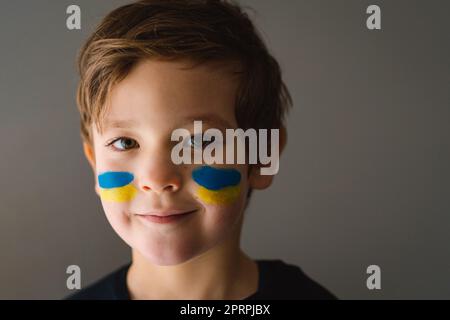 Porträt eines ukrainischen Jungen mit einem Gesicht in den Farben der ukrainischen Flagge. Stockfoto