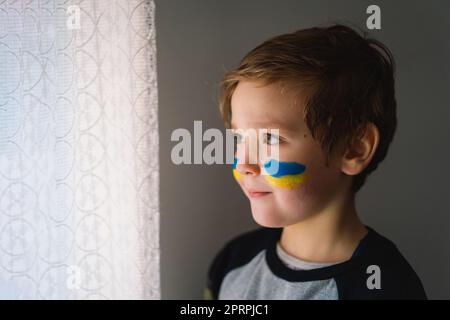 Porträt eines ukrainischen Jungen mit einem Gesicht in den Farben der ukrainischen Flagge. Stockfoto