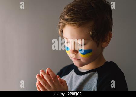 Der ukrainische Junge schloss die Augen und betete, den Krieg in der Ukraine zu beenden. Stockfoto