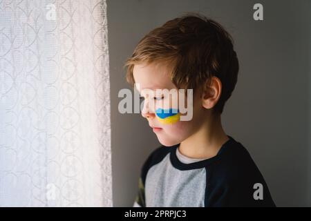 Porträt eines ukrainischen Jungen mit einem Gesicht in den Farben der ukrainischen Flagge. Stockfoto