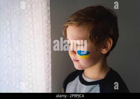 Porträt eines ukrainischen Jungen mit einem Gesicht in den Farben der ukrainischen Flagge. Stockfoto