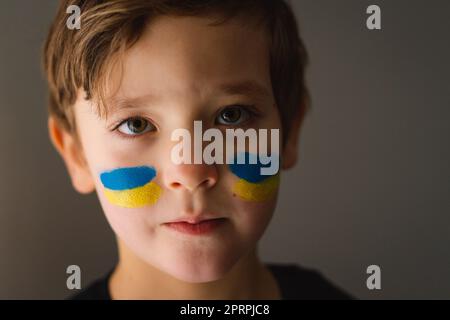 Porträt eines ukrainischen Jungen mit einem Gesicht in den Farben der ukrainischen Flagge. Stockfoto