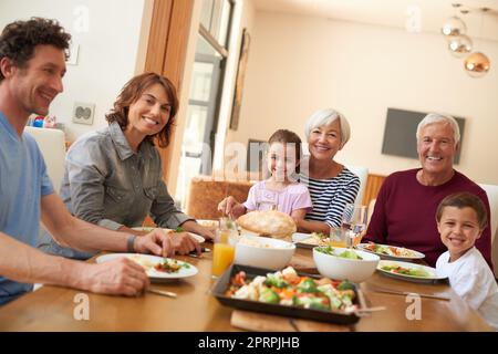 Eine Familie mit mehreren Generationen, die gemeinsam an einem Esstisch essen. Stockfoto