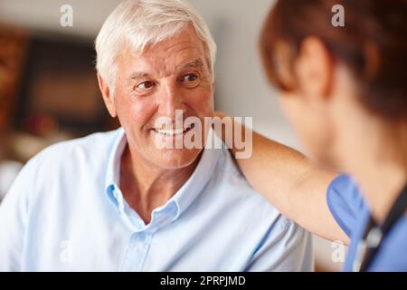 Sie kümmern sich hier gut um ihn. Eine Krankenschwester überprüft ihren älteren Patienten. Stockfoto