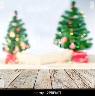 Tischplatte aus Holz auf verschwommenem, farbenfrohem Weihnachtsbaum und goldenem Bokeh-Hintergrund Stockfoto