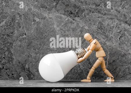 Dummy mit wirtschaftlicher LED-Glühlampe auf Steinhintergrund Stockfoto